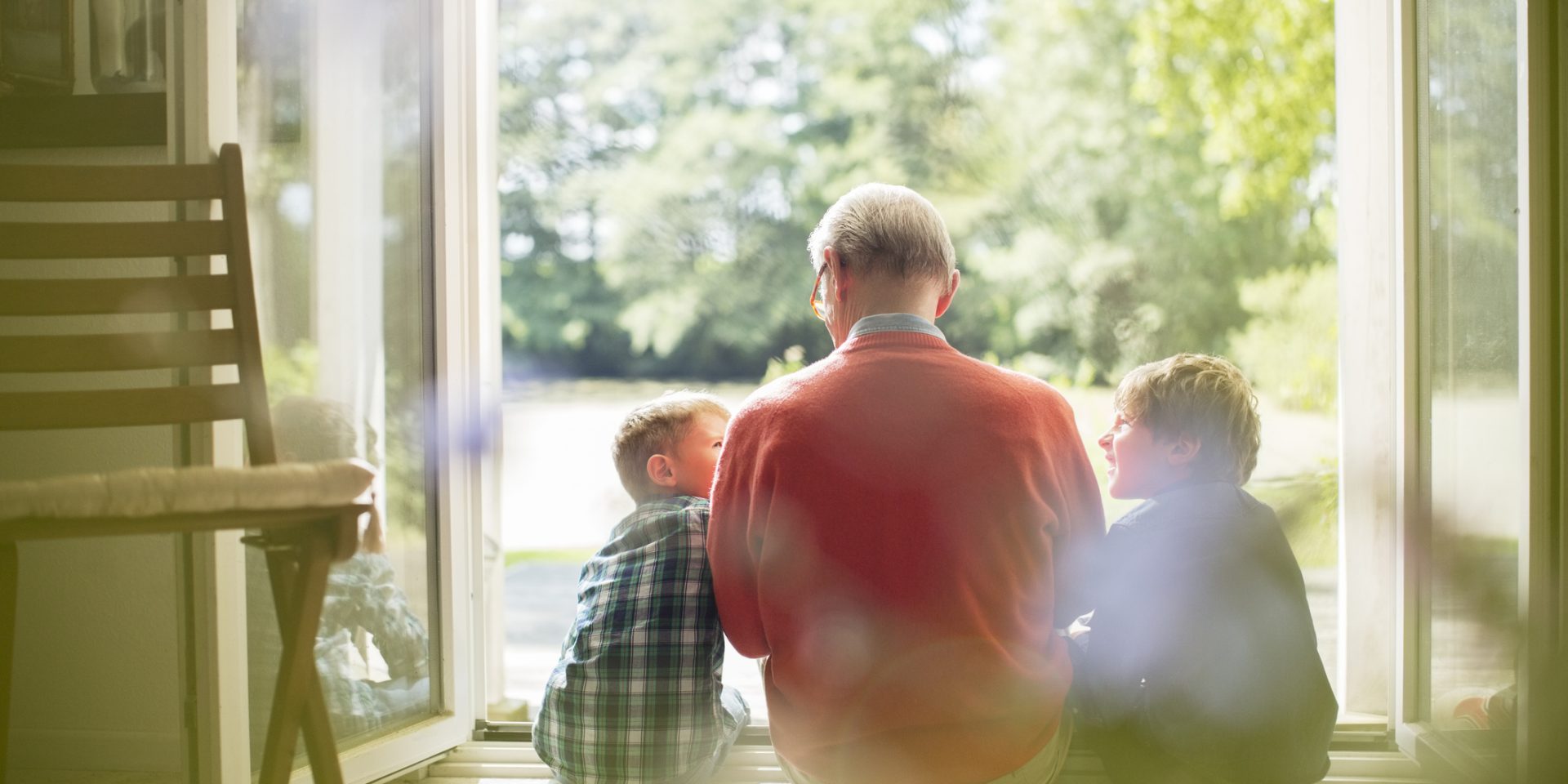 Grandfather and grandsons sitting in doorway