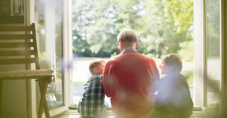 Grandfather and grandsons sitting in doorway